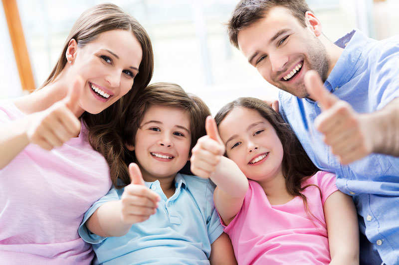 Family of four giving thumbs ups