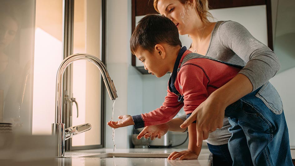 Mom helping a little boy wash his hands