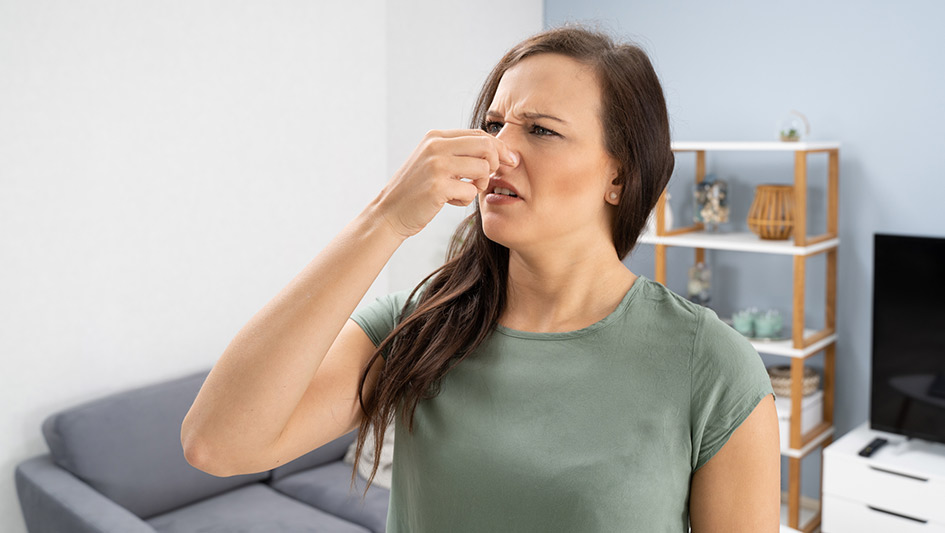 Woman plugging her nose in her house