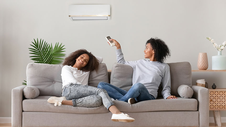Mom and daughter on a couch using a remote with their mini-split