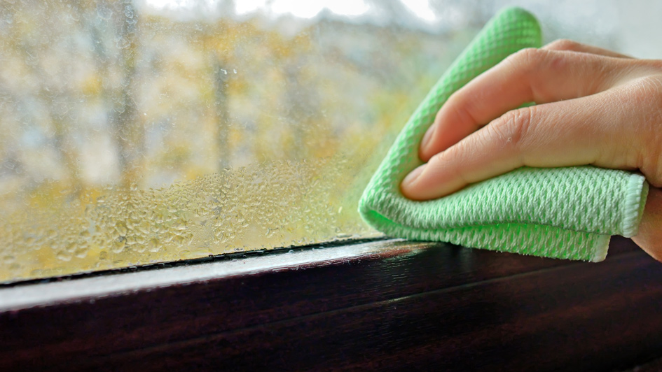man wiping condensation off of a window