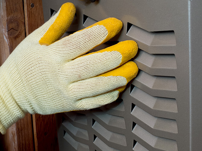 Gloved hand touching an HVAC unit