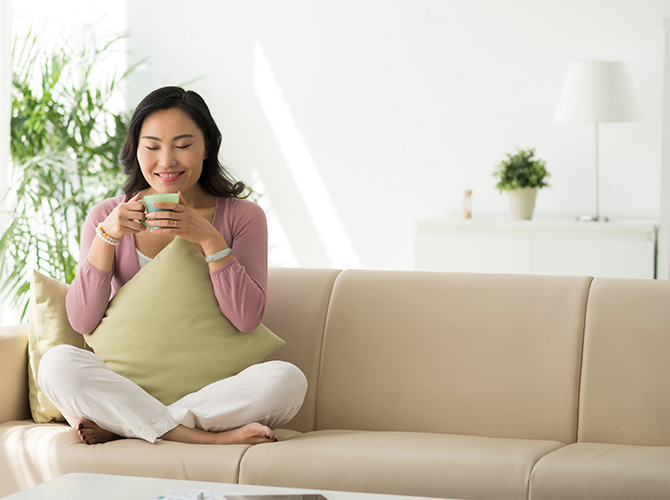 Woman sitting on a couch drinking out of a mug