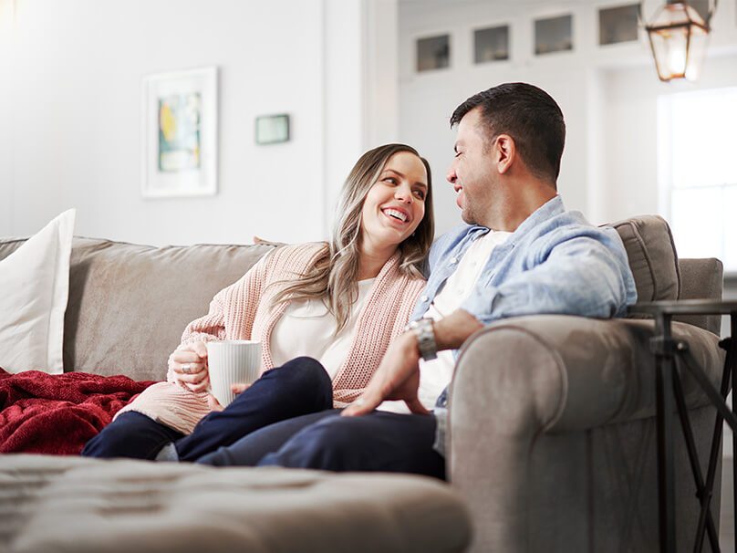 Couple sitting on a couch talking with coffee