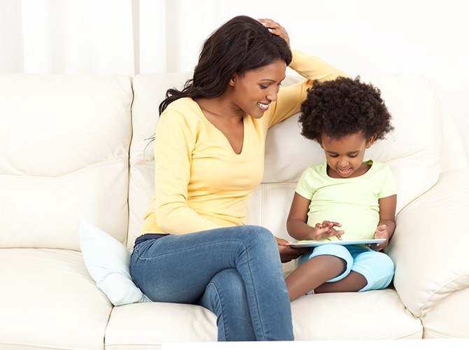 Mother and son playing on an iPad on a couch