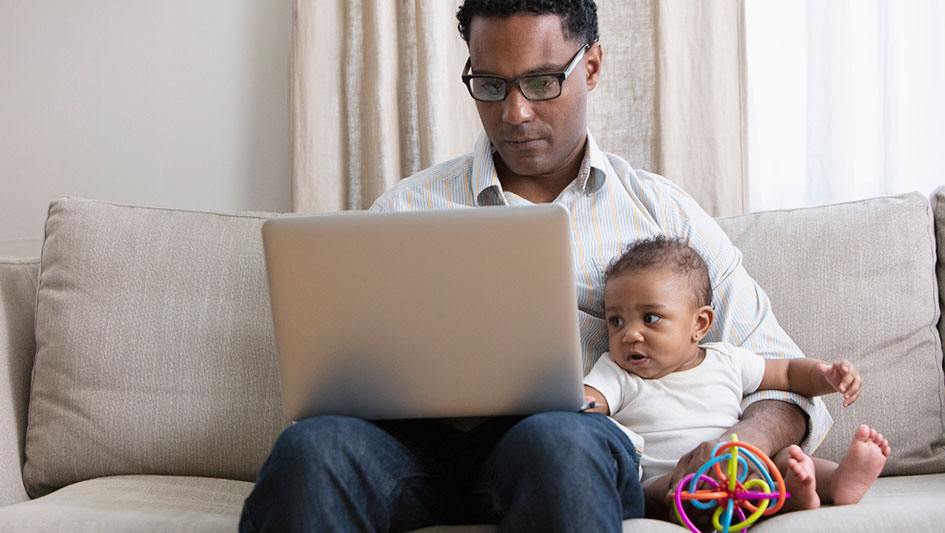 father and baby looking at a laptop on the couch