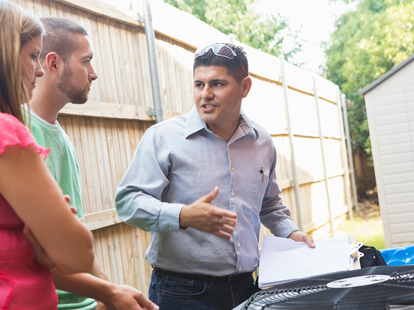 Man talking over an air conditioner with a couple
