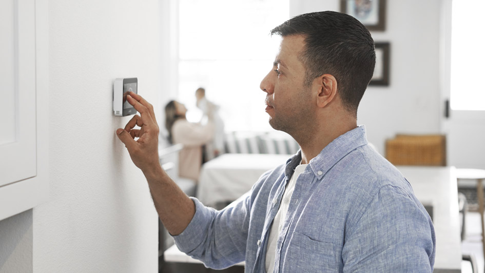 man adjusting a smart thermostat