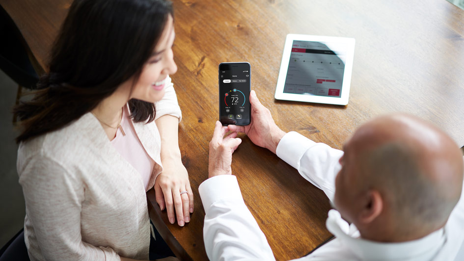woman and HVAC tech looking at smart thermostat settings from a phone