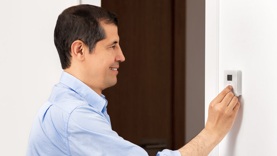 man adjusting a smart thermostat