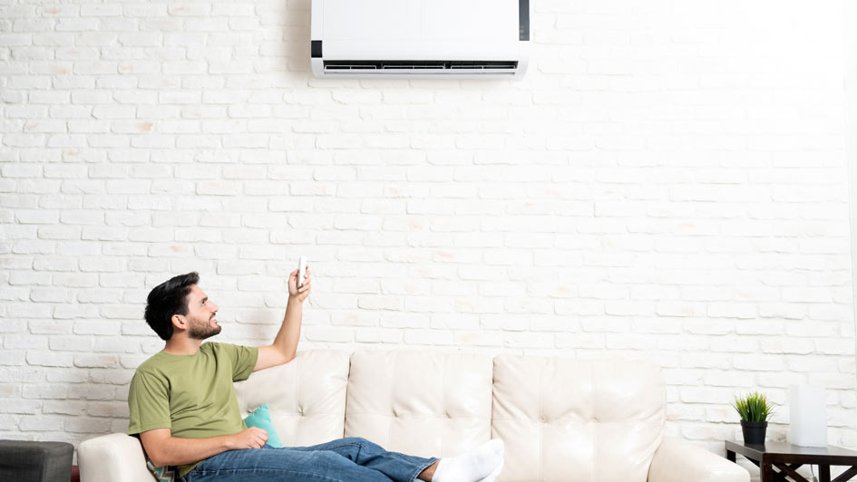 Person sitting on couch and changing mini-split settings with remote