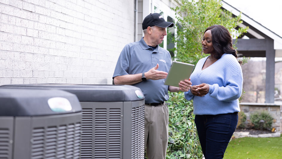 Technician and house owner outside next to air conditioner units