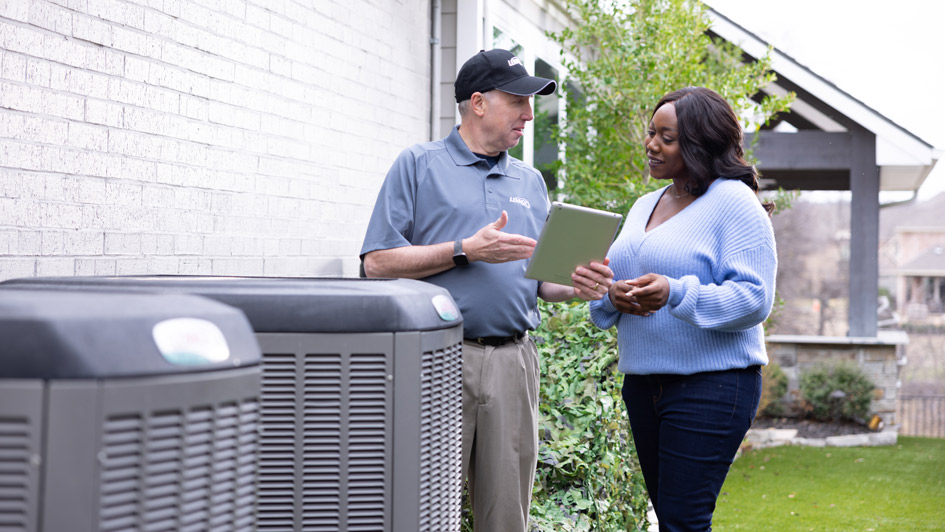 Technician and customer checking heat pumps outside