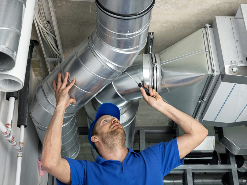 DuctRepair-437190877-808×606 Technician in blue collared shirt performing duct repair