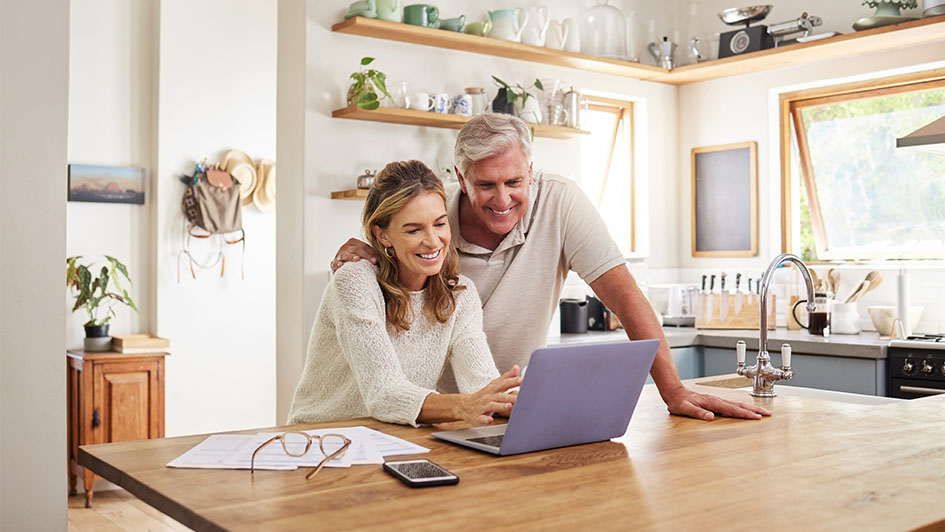 Man and woman smiling while looking at a laptop on the kitchen island