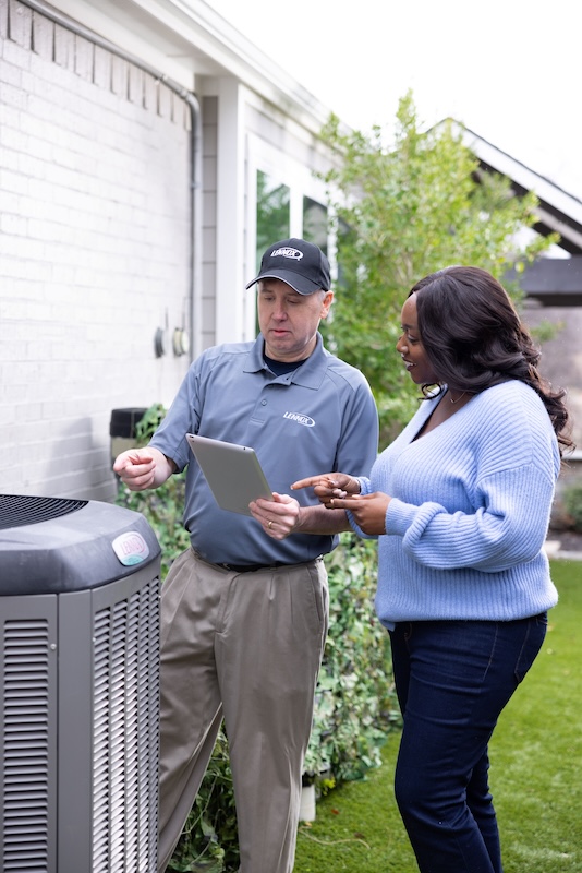 Lennox technician showing a customer a form by her new air conditioner